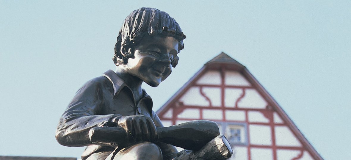 Das Treiser Wahrzeichen auf dem Marktplatz – die markante Brunnenfigur des „Heckedotz“. Das kleine Männlein auf der Spitze des Brunnens erinnert an die Vergangenheit des Dorfes. / Foto: Bruno L. Klamm, Mannheim