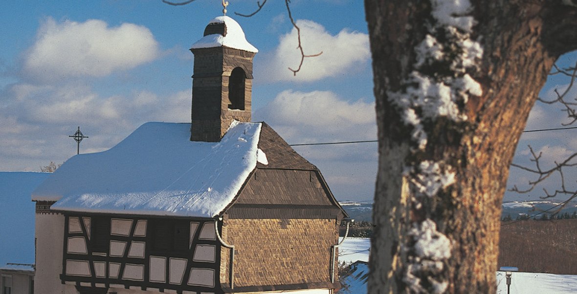 Das 1762 erbaute Glockenhaus prägt den Hattgensteiner Ortskern. Ursprünglich Wohnhaus des Gemeindedieners und Schulhaus, wird es seit 1975 als kleine Kirche genutzt. / Foto: Bruno L. Klamm, Mannheim