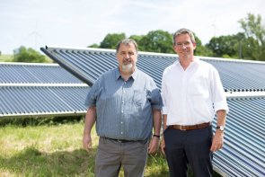 Ortsbürgermeister Volker Wichter und Michael Uhle, Klimaschutzmanager im Rhein-Hunsrück-Kreis, vor dem Solarthermie-Feld, welches das Nahwärmenetz von Neuerkirch-Külz unterstützt. Bild: Energieagentur Rheinland-Pfalz